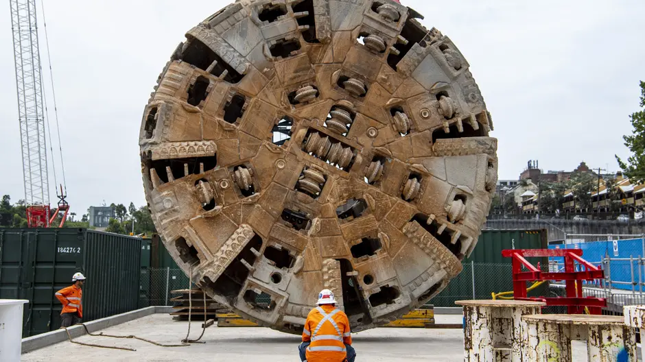 An on the ground view of two construction workers inspecting the Cutterhead Lift of Tunnel Boring Machine (TBM) Mum Shirl at Sydney Metro's at Barangaroo site.