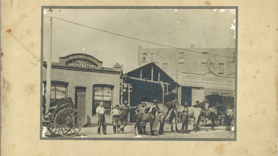 A black and white photo on a faded yellow background of horse and carriages outside of Lambert’s Coach Factory, Crows Nest.