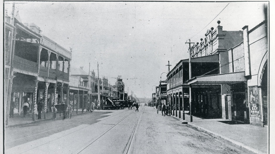 Black and white photo of shops on Marrickville Road near Illawarra Road.