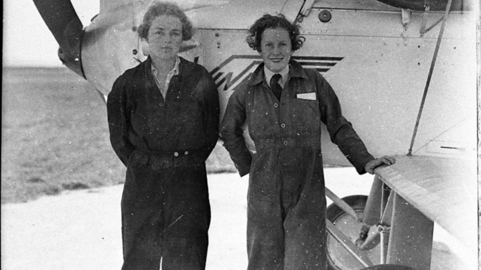 Peggy Kelman (left) with Nancy-Bird Walton (right) standing in front of a plane in pilot gears 