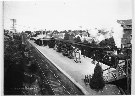 A black and white photo looking down at a station platform as a steam train preparing to depart at Chatswood Railway Station in 1910. 