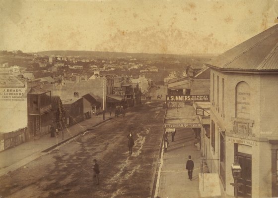 Old and damaged photograph of people walking down a street in North Sydney.