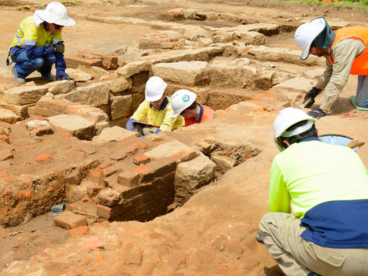 Five construction workers inspecting the ground for archaeological artefacts during the excavation at Sydney Metro's White Hart Inn site.