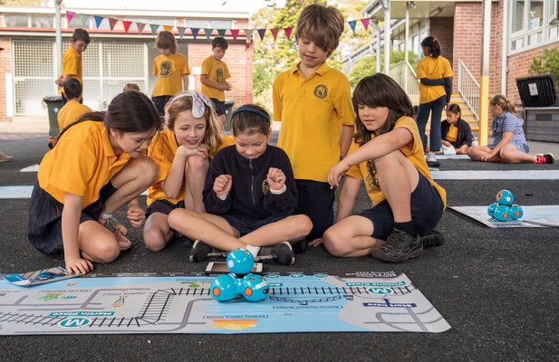 Five students from Petersham Public School smiling behind the dash robot that is sitting on top of an alignment map