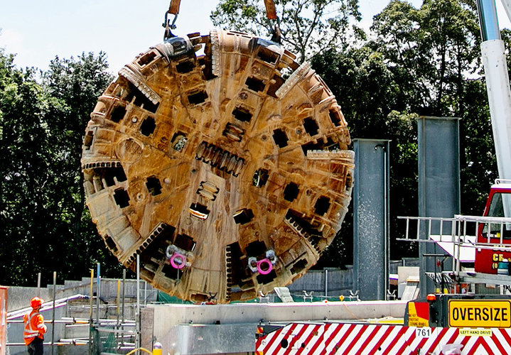 TBM4 Maria cutterhead is being lifted from Epping construction site while construction workers look on.