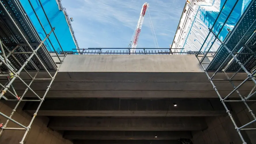 View from below of platforms installed at Waterloo Station. A large crane and sky is in the background.