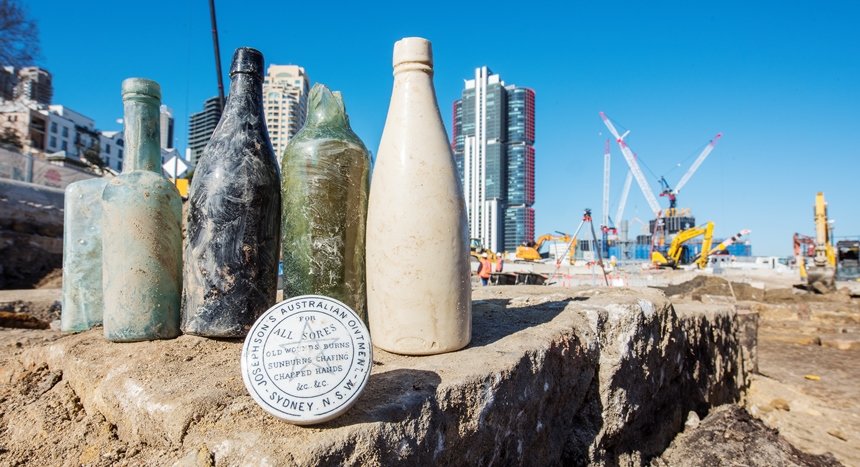5 old glass bottles and an old jar that reads 'Josephson's Australian Ointment' are on display at the excavation area at the future site of Barangaroo Metro Station.