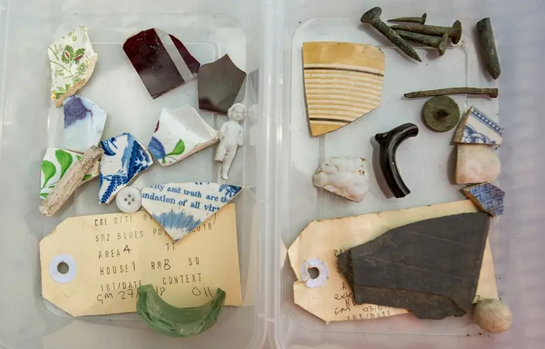 Old artefacts that were found at Blues Point construction site are featured inside a clear plastic container. Some include broken china, glass, a button, and an old label.