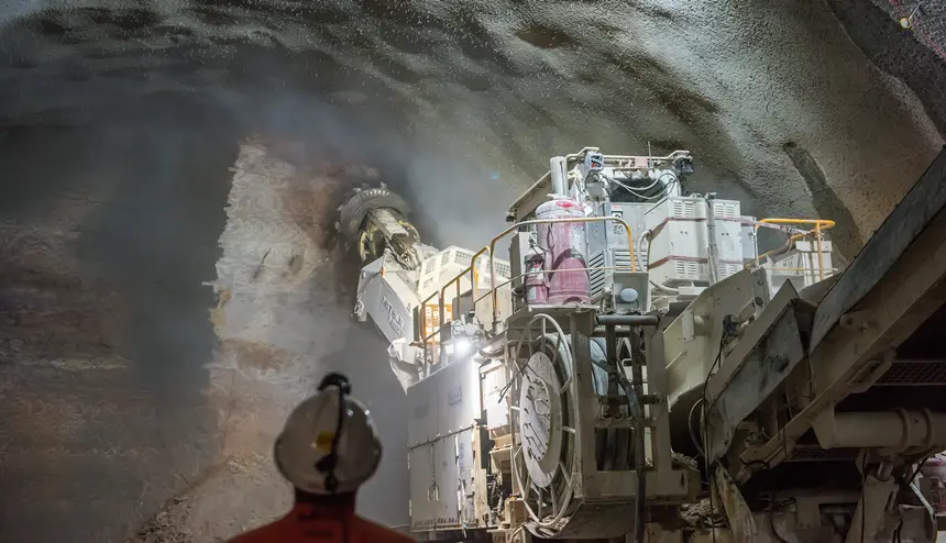 A large Roadheader is working inside the tunnels underneath Bligh Street while a construction worker looks on.
