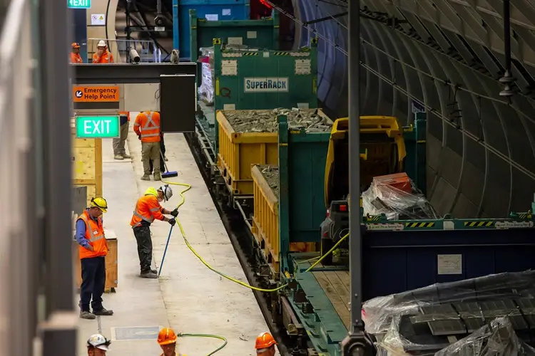 An arial view showing four construction workers on the platform as a freight train is delivering materials to the platform at East Coast Rail Link's Macquarie Park Station.