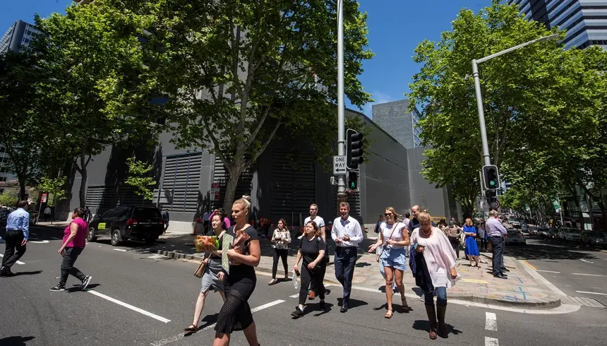 A group of people crossing the road commuting outside of Sydney Metro's Victoria Cross South Acoustic Shed.