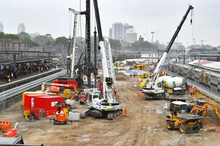 An arial view looking across at the construction site of the Sydney Metro station box at Central Station with many heavy machinery on the ground between the platforms.