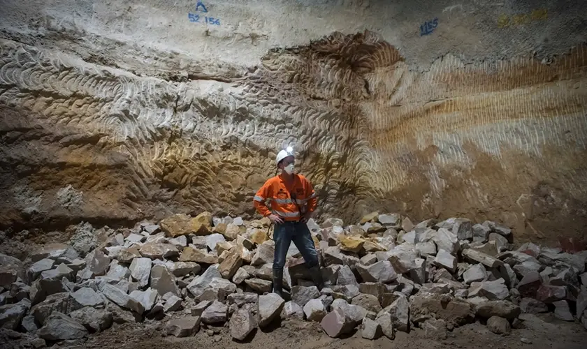 An on the ground view showing a construction worker standing in front of a pile of sandstone that has been taken down as construction continues at Sydney Metro's Martin Place Station.