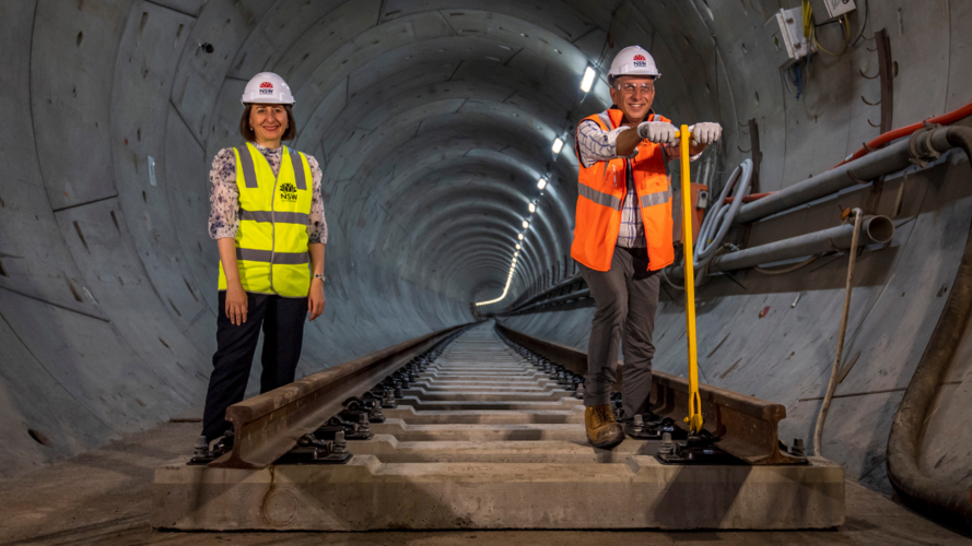 The NSW Premier and Minister for Transport standing on newly laid rail track in the tunnel at Chatswood. 