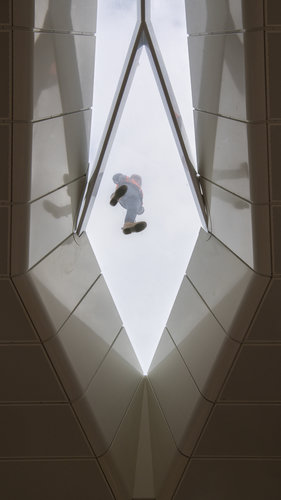 Looking up at Central Station vaulted roof. A construction worker is seen standing on top of the glass roofing 