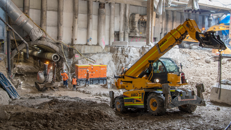 A yellow excavator digs up spoil at the entry to the construction tunnel within the metro box at Central Station.