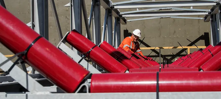 A close up shot as three construction workers are installing metal panels of the conveyer belt at Sydney Metro's Chatswood Drive.