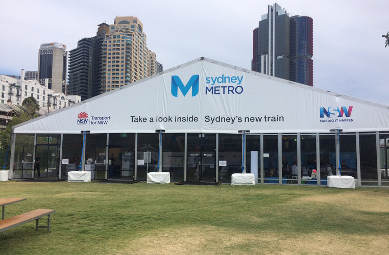 A large Sydney Metro branded marquee displaying the words 'take a look inside Sydney's new train' which was displayed at Barangaroo Reserve.