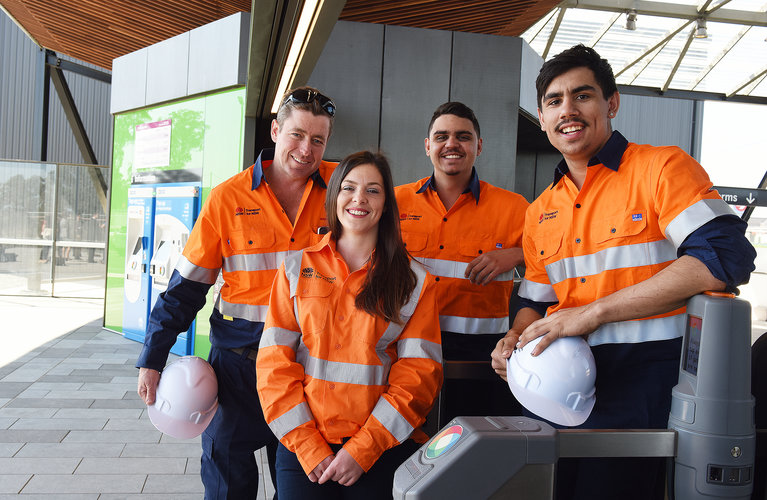 A group shot with the Infrastructure Skills Legacy Program Premier and three apprentices stood at the gate barriers at a Sydney Metro Station.