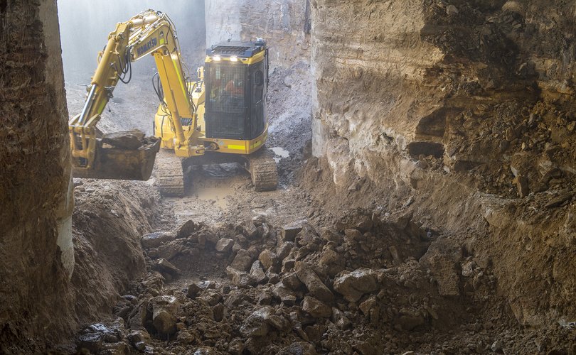 A yellow excavator digs up spoil inside the Central Station construction site.