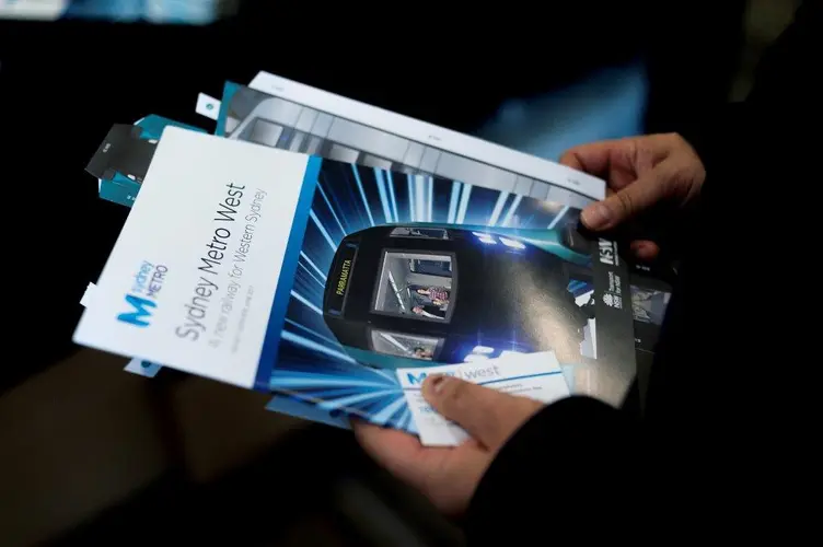 A close up shot of a community member holding some Sydney Metro West flyers received at the community information centre at Westmead Hospital. 