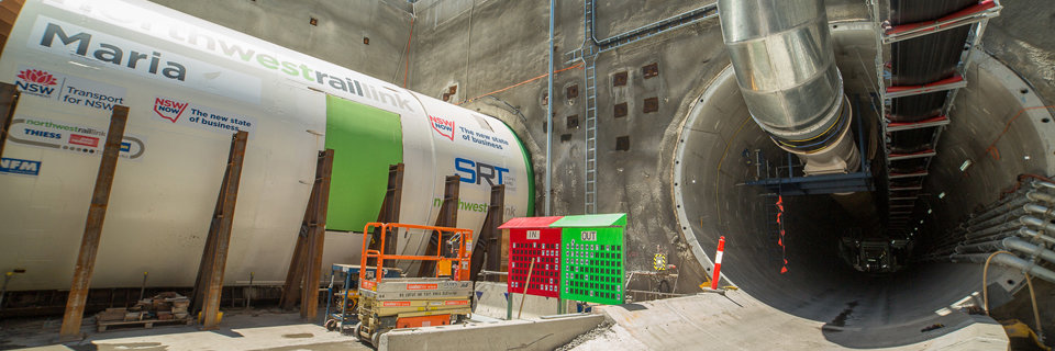 An on the ground view looking across to Tunnel Boring Machine (TBM) 4 Maria showing green in sign and red out side for the twin tunnels at a Sydney Metro construction site for the West Railway Link.