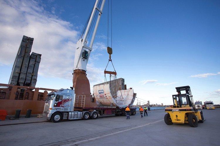 An on the ground view showing Tunnel Boring Machine (TBM) 1 Elizabeth being craned onto a large truck as it arrives in Australia.
