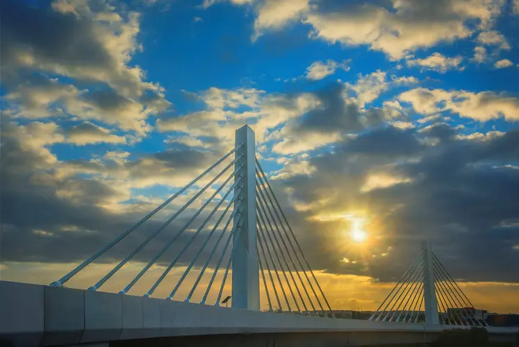 An arial view showing the completed Cable Stay Bridge with a beautiful sky as the sun peeps through a cloud in the background at Sydney Metro's Rouse Hill.