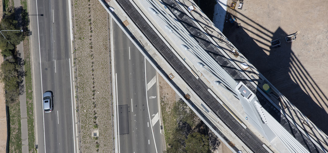 A bird's eye view of Sydney Metro's Windsor Road bridge being constructed, there are cars traveling on the road below.