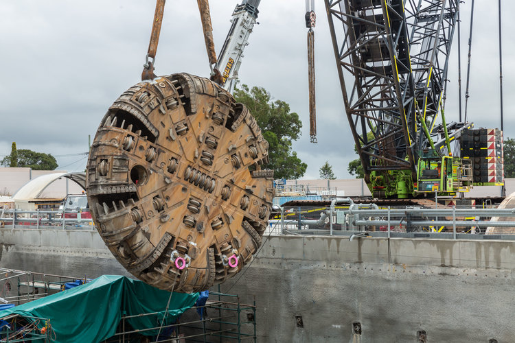 The cutterhead of a Tunnel Boring Machine (TBM) is being retrieved as it is being lifted out of the construction site by a crane as work nears completion on the Sydney Metro's Northwest project. 
