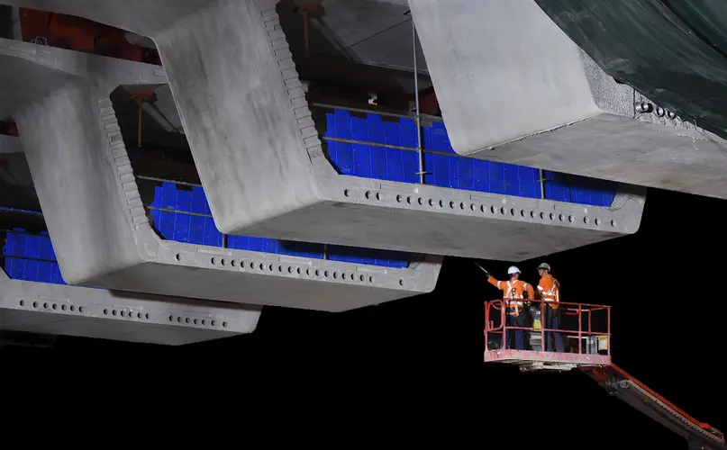Two construction workers on a crane inspecting the bridge deck on the Windsor Road railway bridge at Sydney Metro's Rouse Hill Station.