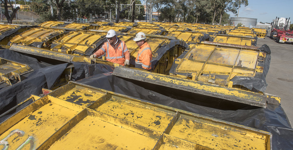 Two construction workers inspecting the moulds of the Sydney Metro trains lined up in the background.