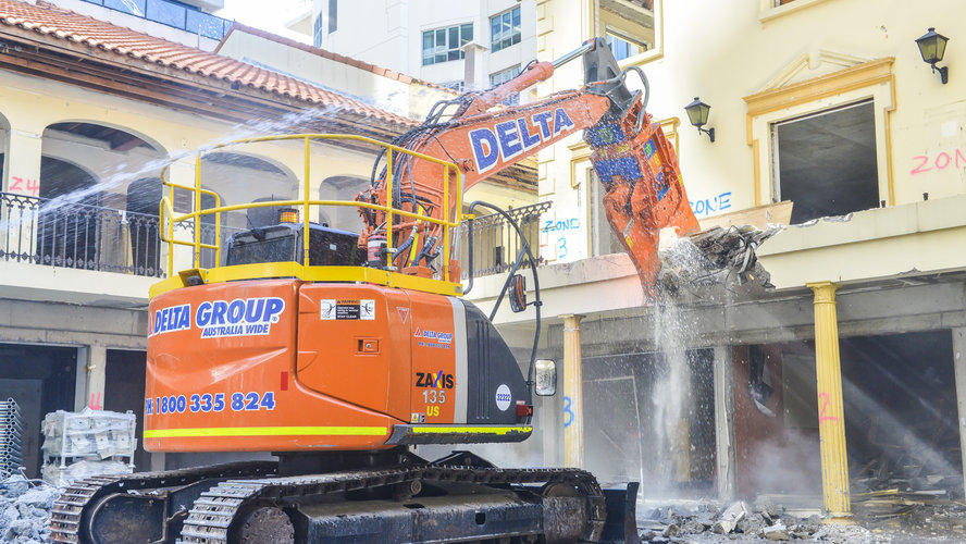 An on the ground view showing the Excavator attachment the pulveriser as it begins demolition of a building at a Sydney Metro construction site. 