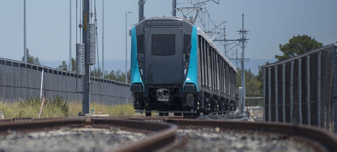 An on the ground shot looking at a Sydney Metro train coming towards the camera being tested along the tracks.