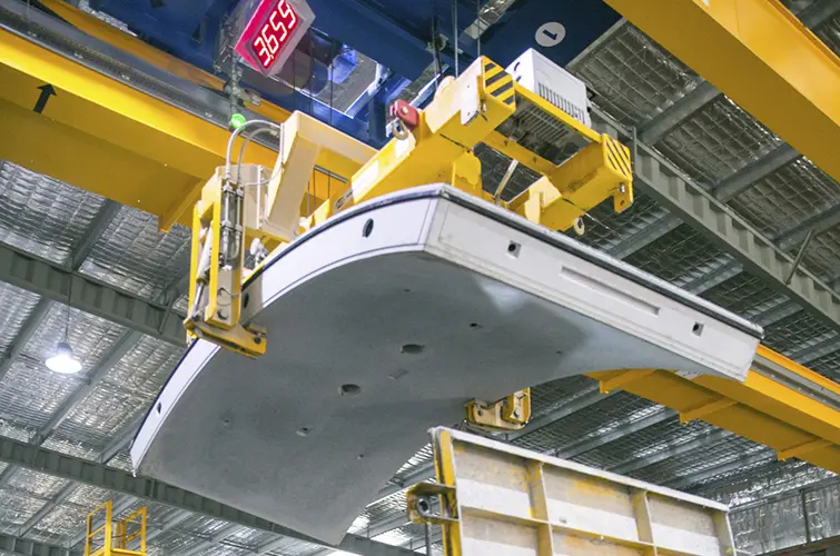 A close up shot looking up at the final concrete segment being lifted into place by the crane above.