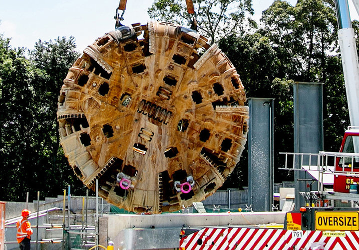 An on the ground view showing a construction worker inspecting the cutterhead of Tunnel Boring Machine (TBM) being retrieved at Sydney Mero's Epping station. 