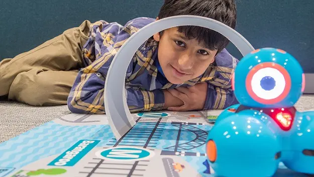 A student poses with a robot while participating in the fun with robots workshop as part of Sydney Metro's Education Program.