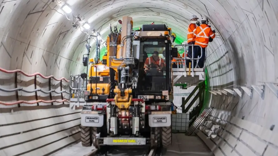 Workers aboard a M&E consist install the infrastructure for the mechanical and electrical systems inside Sydney Metro's down tunnel.