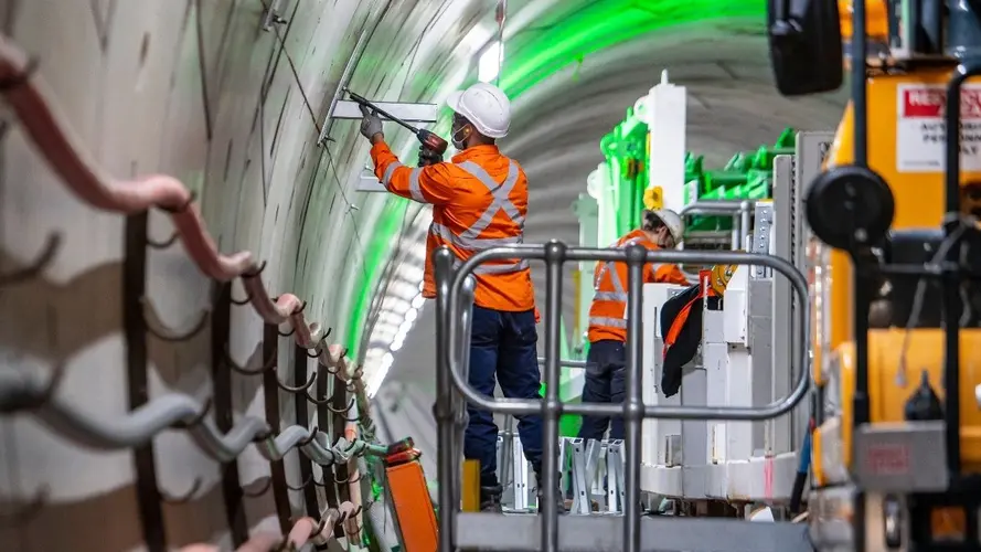 Workers aboard a M&E consist install the infrastructure for the mechanical and electrical systems inside Sydney Metro's down tunnel.