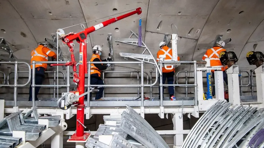 Workers aboard a M&E consist install the infrastructure for the mechanical and electrical systems inside Sydney Metro's down tunnel.