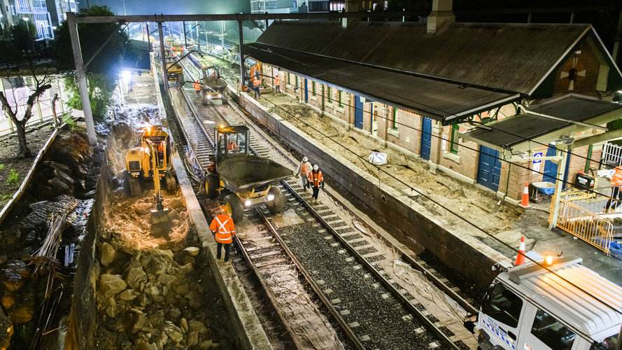 A bird's eye view of construction workers in orange high-vis performing night time track works at Canterbury Station.