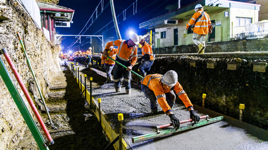 An on the ground view of construction workers laying the concrete on the tracks at Sydney Metro's Wiley Park Station.