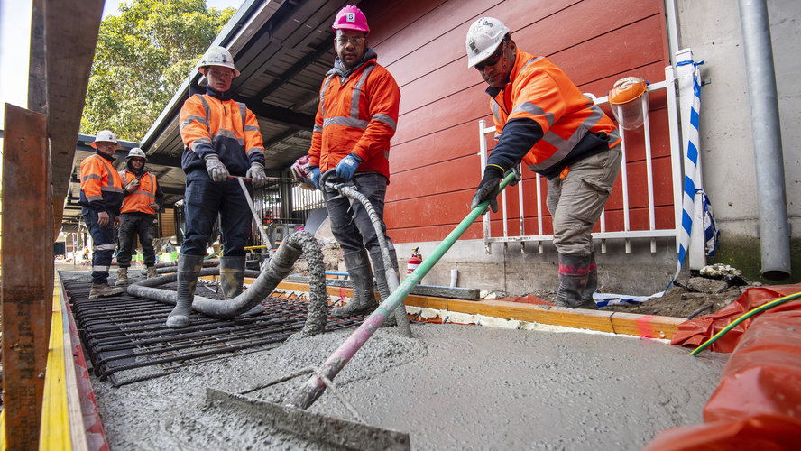 An on the ground view of construction workers laying the concrete on the tracks at Sydney Metro's Marrickville Station.
