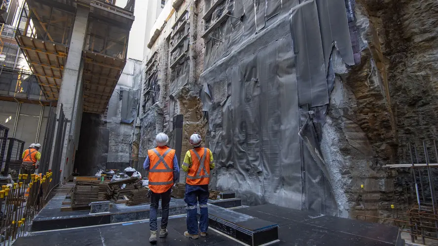 Two construction workers look up at the waterproofing works at Pitt Street North site.