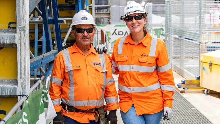 Two construction workers smiling on site on B3 level at Sydney Metro's Waterloo Station.