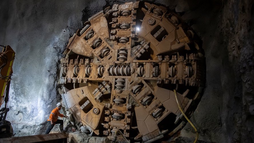 Construction worker inspecting Tunnel Boring Machine (TBM) Kathleen breaking through at Sydney Metro's Blues Point tunnel access site. 