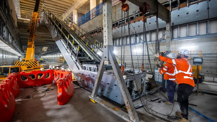Two construction workers installing an escalator underground at Barangaroo Station.