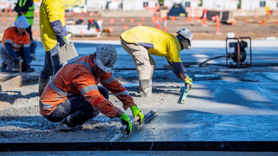 An on the ground view of construction workers levelling wet concrete on Sydney Metro's Eastern Creek Station precast site. 