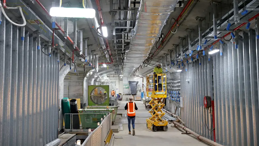 Construction worker walking through the underground caverns at Sydney Metro's Martin Place Station.
