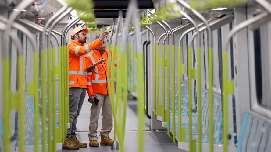 Two construction workers inside metro train carriage assessing safety.